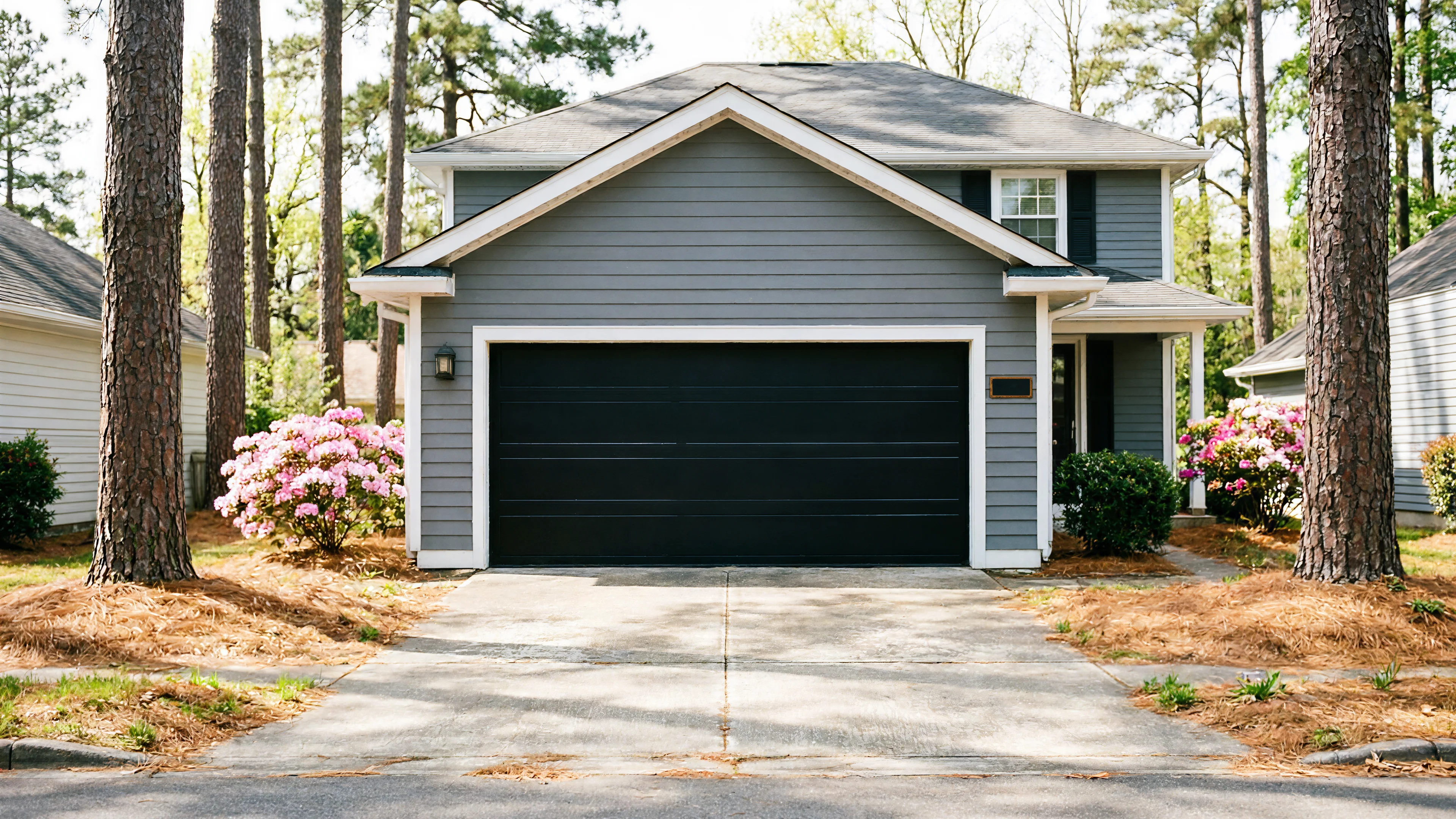 A gray house with a black garage door and a concrete driveway.